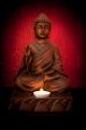 Buddha Statue With a Candle On a Red Background Canvas Print